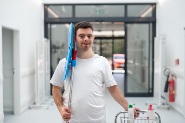 Young man with down syndrome working in hospital as cleaner. Concpet of integration people with disability into society.