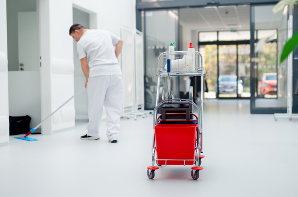 Young man with down syndrome working in hospital as cleaner. Concpet of integration people with disability into society.