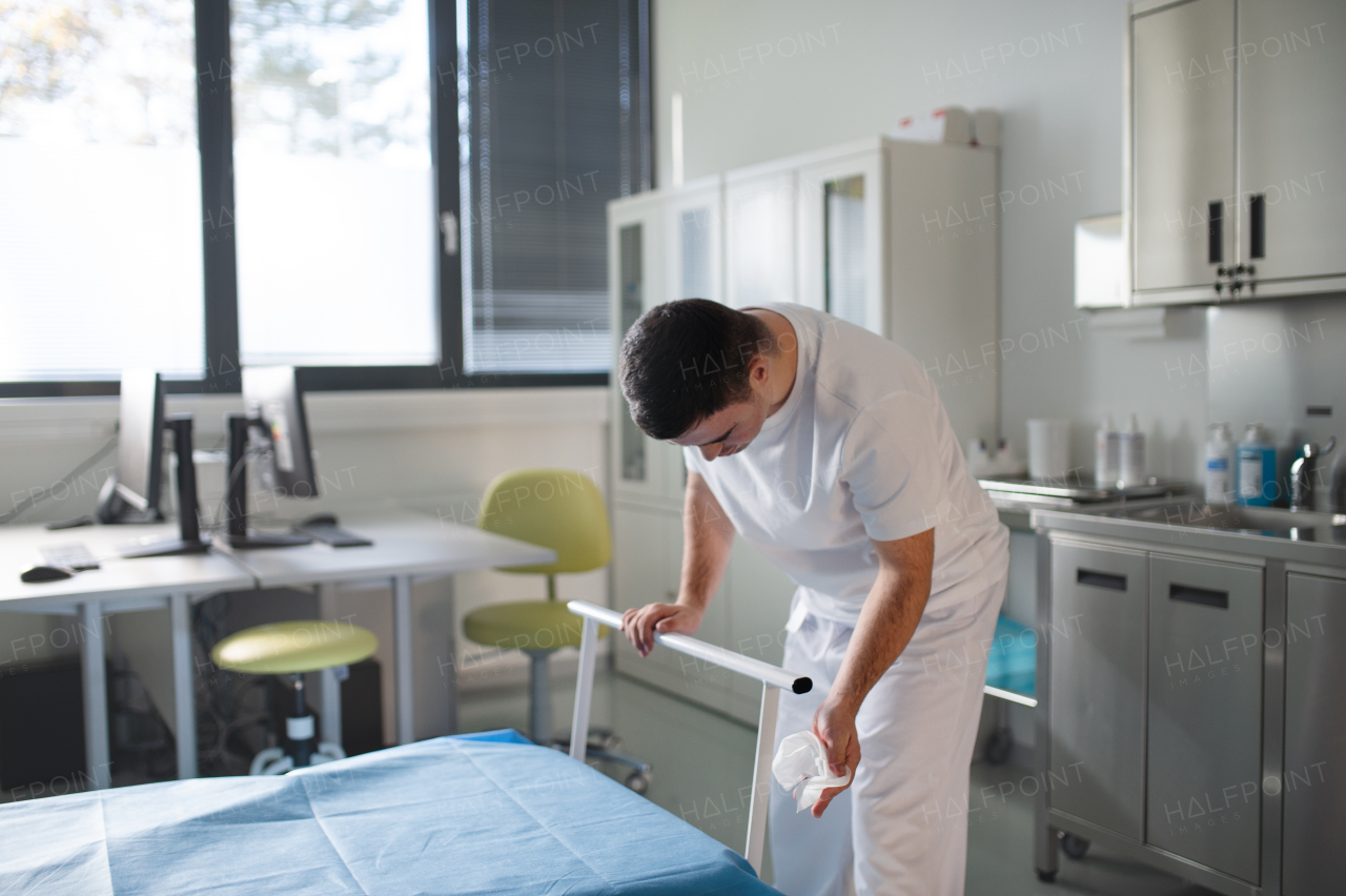 Young man with down syndome working in a hospital as helper, cleaner. Concpet of integration people with disability into society.