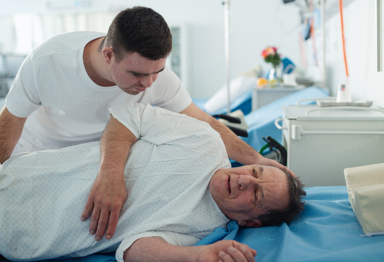 Young man with down syndome working in a hospital as a caregiver. Concpet of integration people with disability into society.