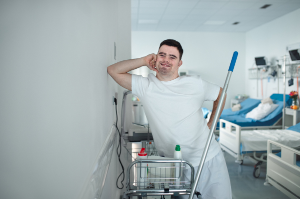 Young man with down syndrome working in hospital as cleaner. Concpet of integration people with disability into society.