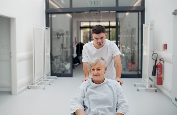 Young man with down syndome working in a hospital as a caregiver. Concpet of integration people with disability into society.