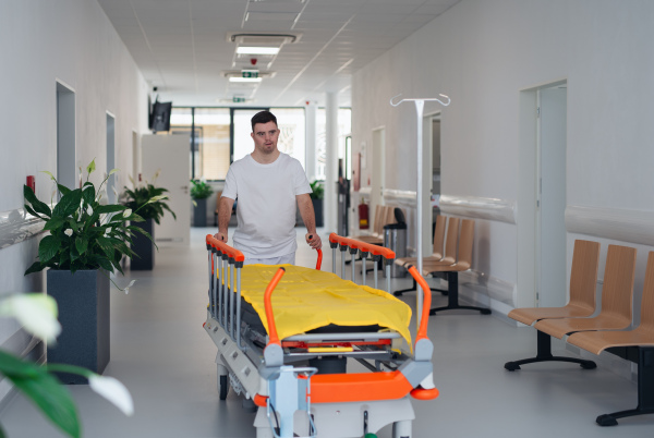 Young man with down syndome working in a hospital as a caregiver. Concpet of integration people with disability into society.