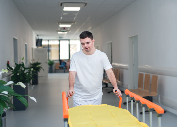 Young man with down syndome working in a hospital as a caregiver. Concpet of integration people with disability into society.