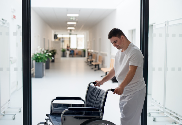 Young man with down syndome working in a hospital as a caregiver. Concpet of integration people with disability into society.