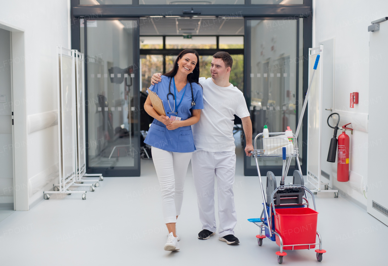 Young man with down syndrome working in hospital as cleaner, talking to nurse, having fun. Concpet of integration people with disability into society.