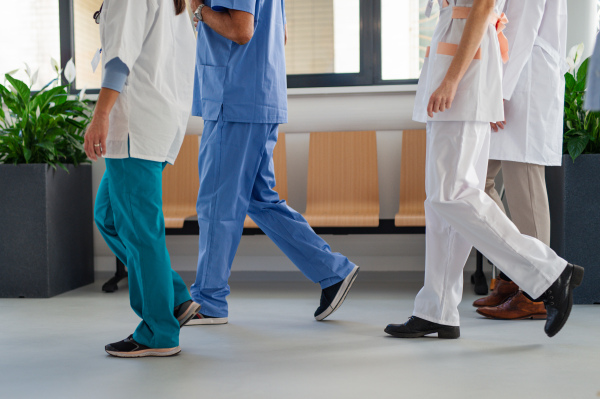 Low angle view of the medical staff at hospital corridor, going for daily chceck up of patients.