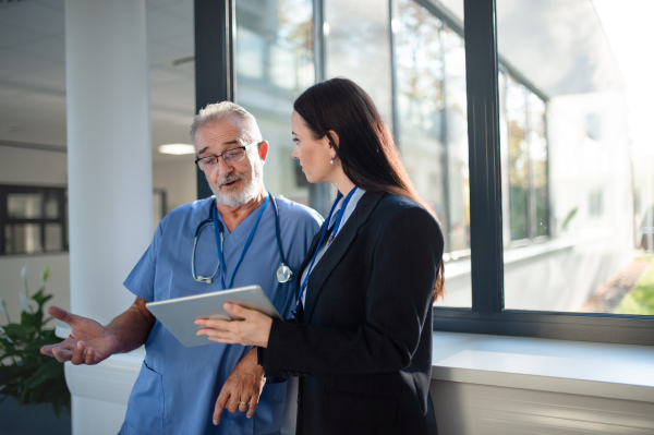 Young business woman shaking hand with elderly doctor in a hospital.