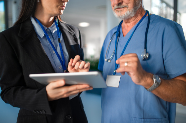 Young business woman shaking hand with elderly doctor in a hospital.