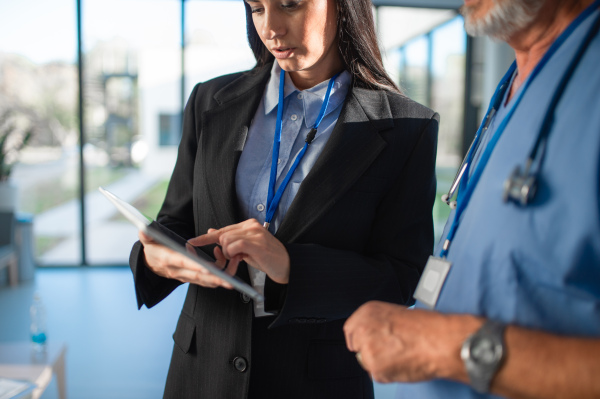 Young business woman shaking hand with elderly doctor in a hospital.