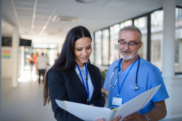 Doctor and business woman in hospital reading documents in a hospital corridor.