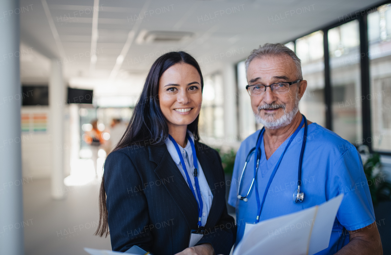 Portrait of elderly doctor and business woman at a hospital corridor.