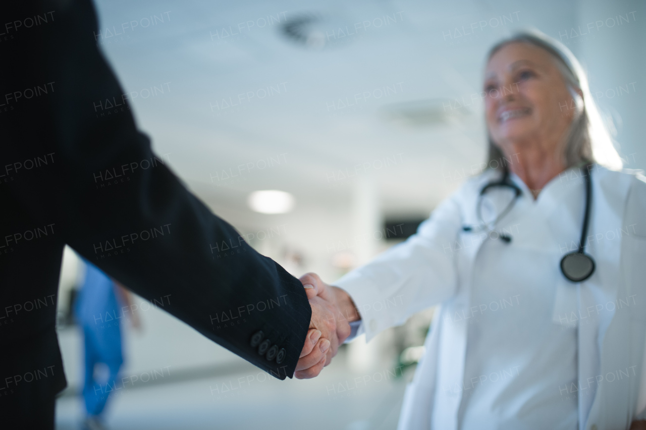 Close-up of handshake of doctor and business person.