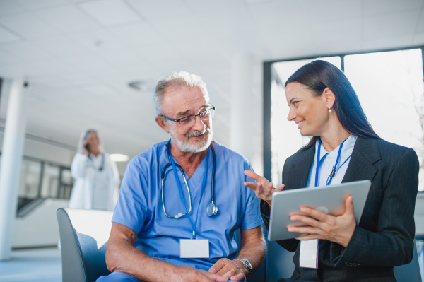 Young business woman shaking hand with elderly doctor in a hospital.