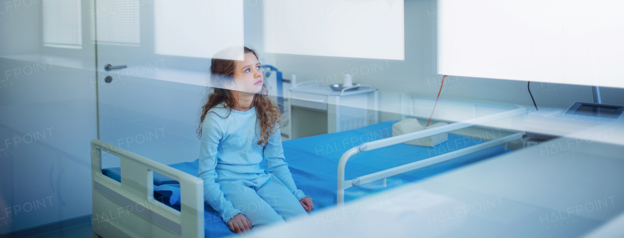 Little sick girl sitting alone in a hospital ward.