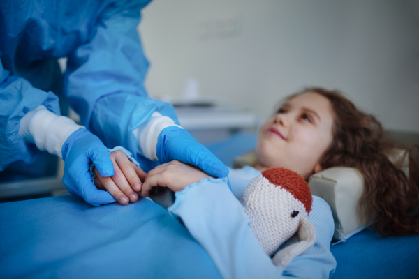 Close-up of doctor taking care of little girl in a hospital ward.