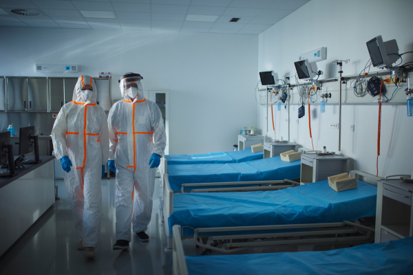 Doctors in a protective coveralls in hospital room, infectious disease concept.