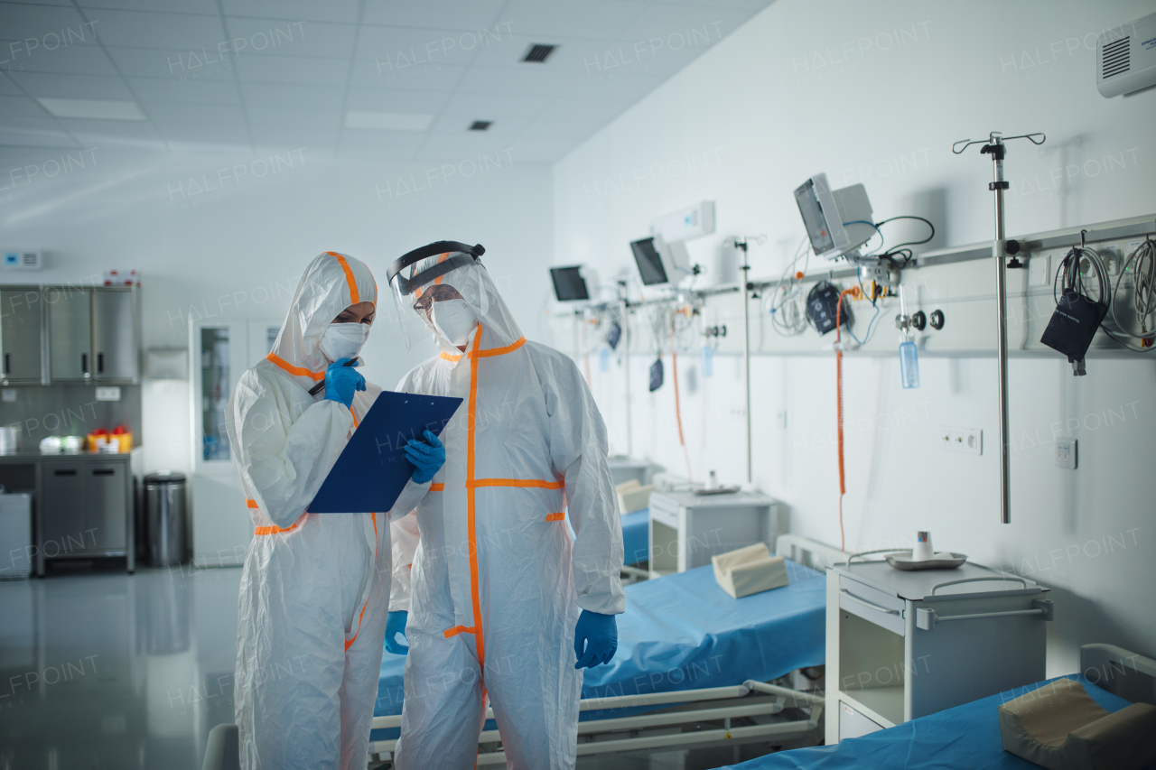 Doctors in a protective coveralls in hospital room, infectious disease concept.