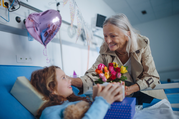 Granmother visiting her sick granddaughter in a hospital, celebrating her birthday.