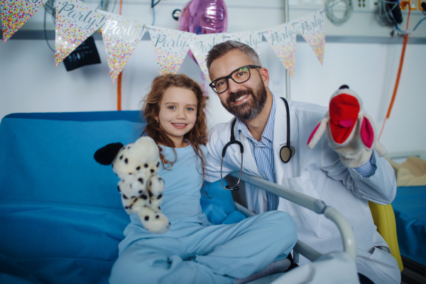 Friendly doctor taking care and playing with little patient.