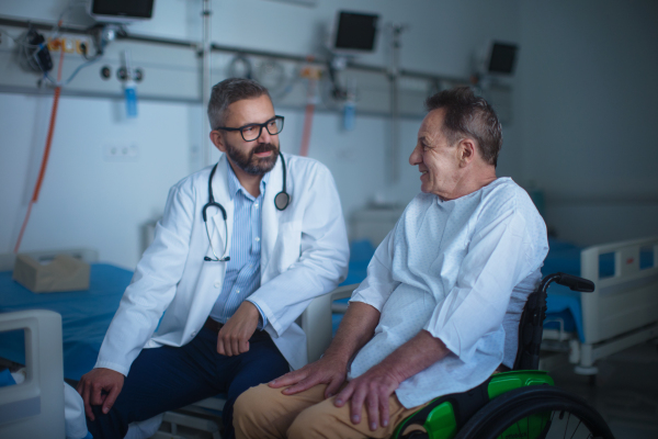 Mature doctor explaining diagnosis to her patient in hospital room.