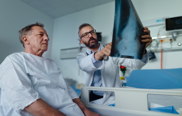 Mature doctor showing elderly patient x-ray image of his lungs.