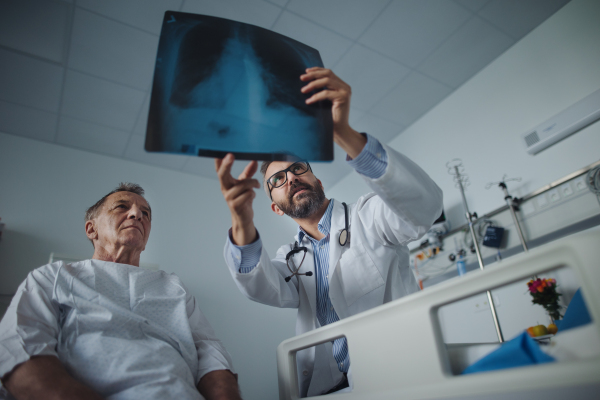 Mature doctor showing elderly patient x-ray image of his lungs.