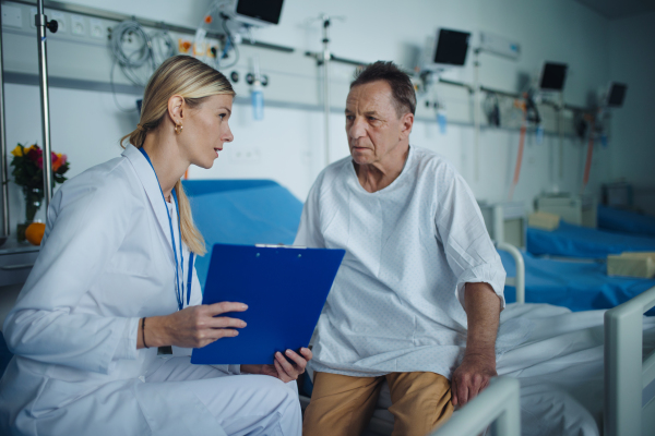 Young woman doctor explaining diagnosis to her patient in hospital room.