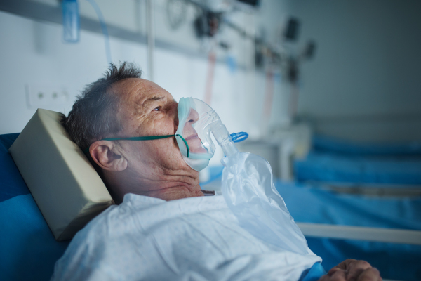 Senior man with oxygen mask lying in the hospital.