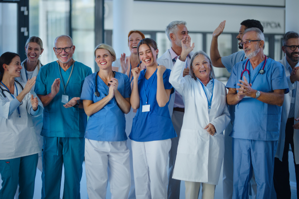 Portrait of happy doctors, nurses and other medical staff clapping, in a hospital.