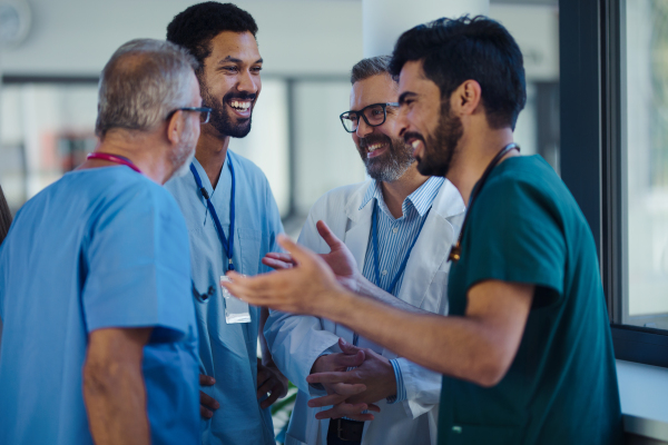 Happy doctors talking and smiling at a hospital corridor.