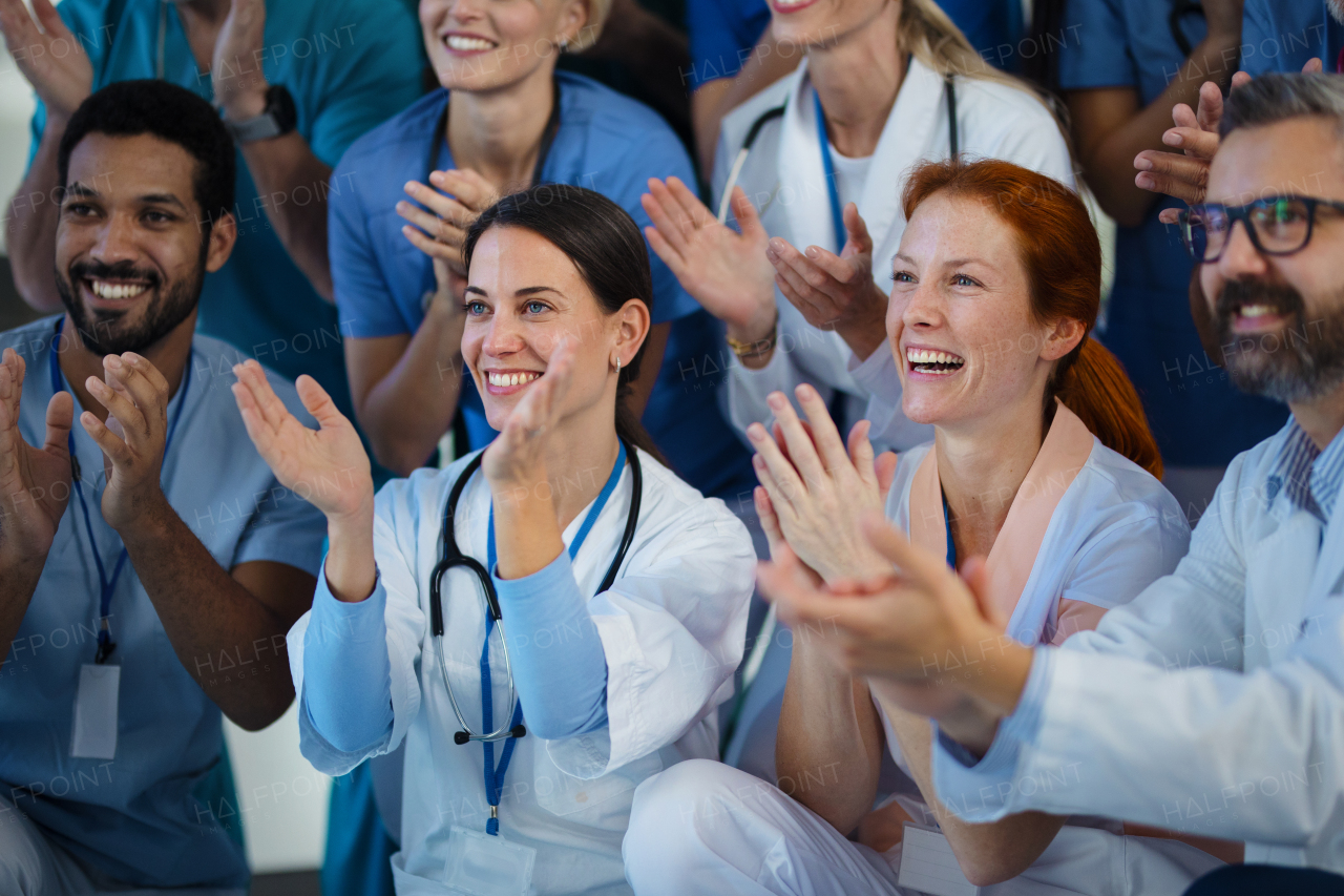 Portrait of happy doctors, nurses and other medical staff clapping, in a hospital.