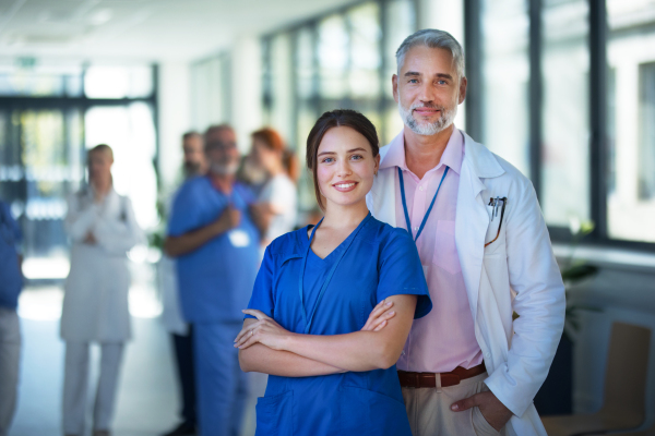 Portrait of young woman doctor with her elder colleague at a hospital corridor.