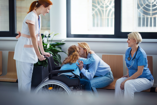 Little girl on wheelchair greeting with her mother in a hospital.