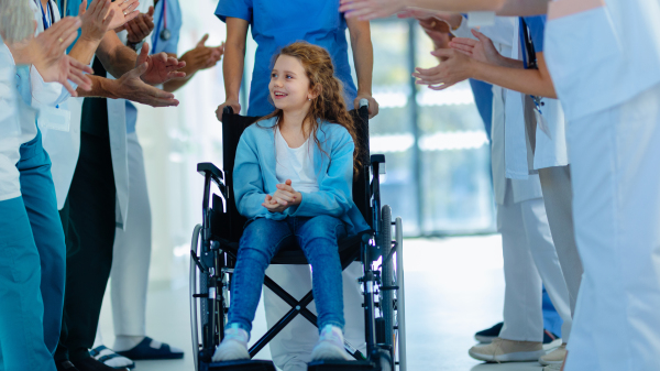 Medical staff clapping to patient who recovered from a serious illness.