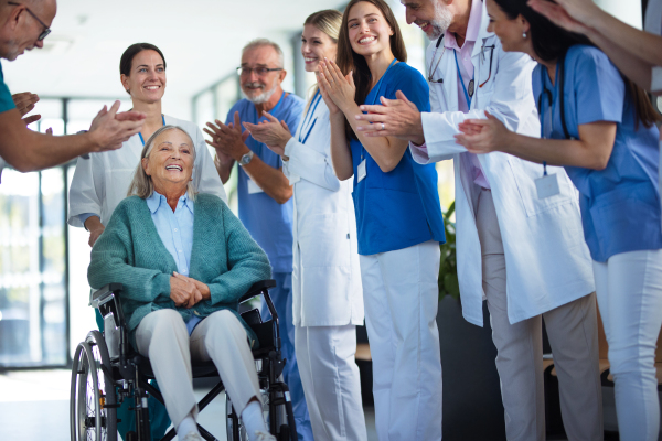 Medical staff clapping to patient who recovered from a serious illness.