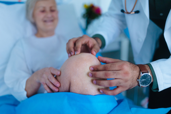 Young doctor examining senior patient in hospital room.