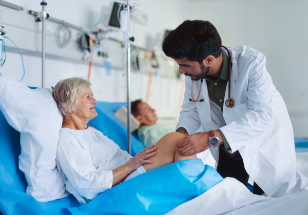 Young doctor examining seniors patients in hospital room.