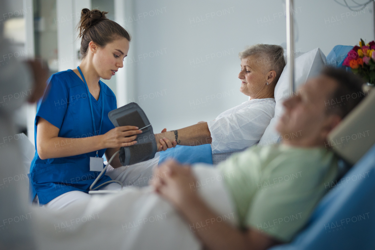 Young nurse measuring blood presure to senior patient.