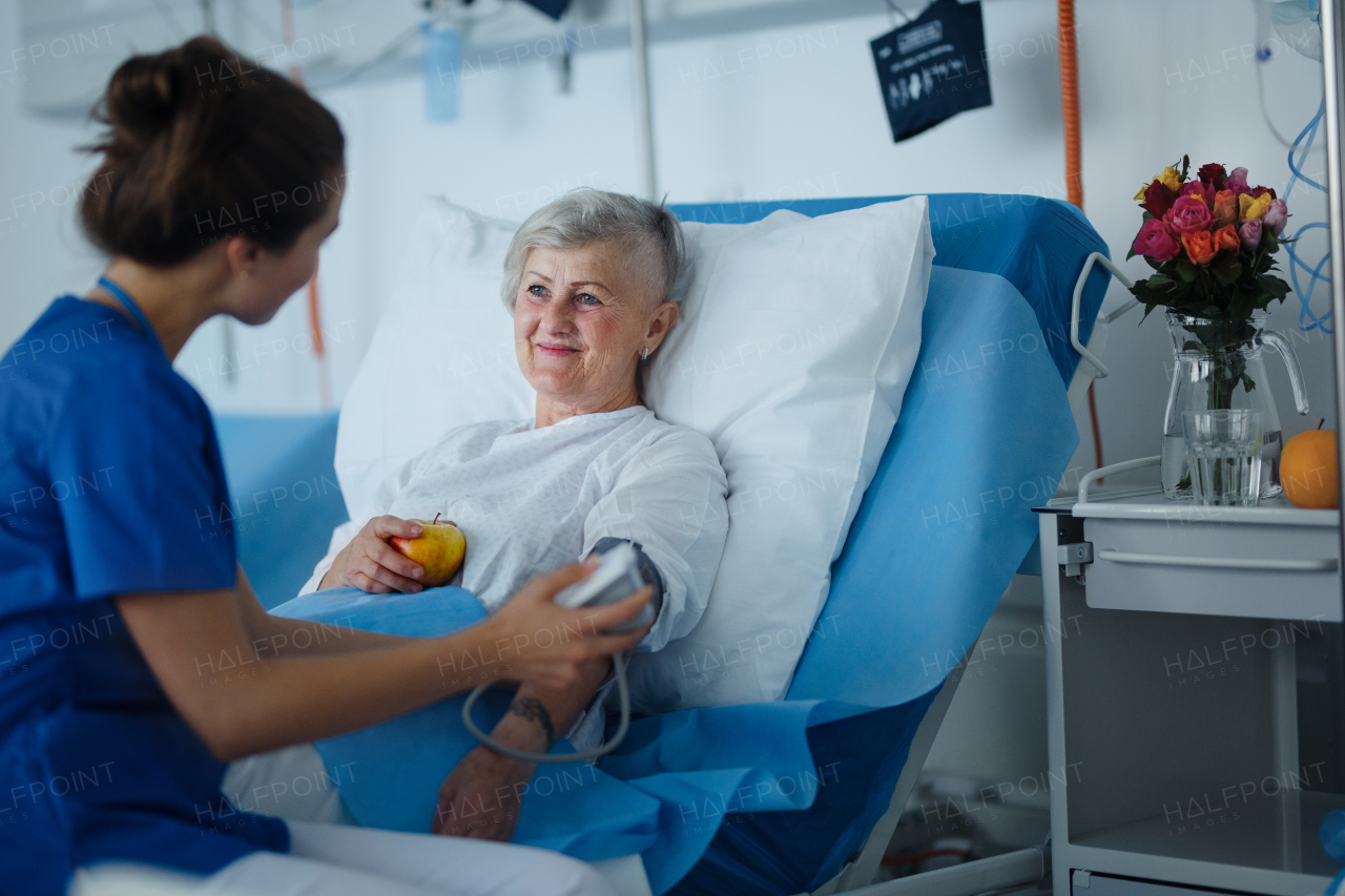 Young nurse measuring blood presure to senior patient.