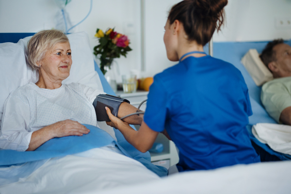 Young nurse measuring blood presure to senior patient.