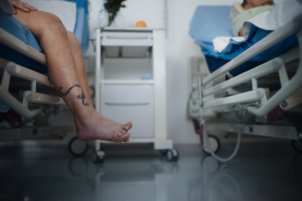 Close-up of womans leg trying to get out of a hospital bed.