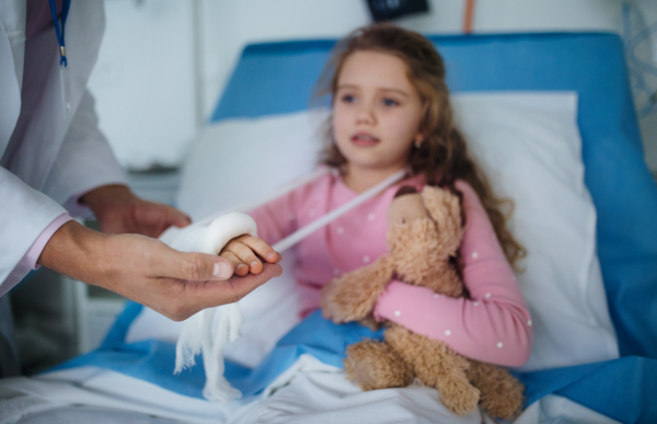 Doctor examining a little girl with broken arm.