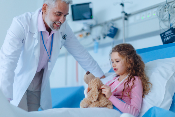 Friendly doctor taking care and playing with little patient.