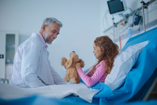 Friendly doctor taking care and playing with little patient.