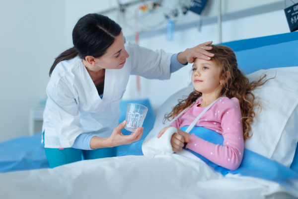 Young nurse giving glass of water to the little girl.