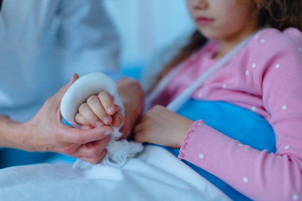 Doctor examining a little girl with broken arm.