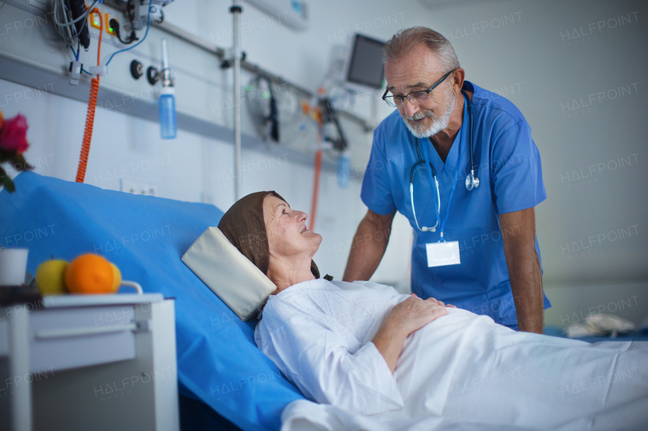 Elderly doctor examining patient in a hospital room, talking with her.