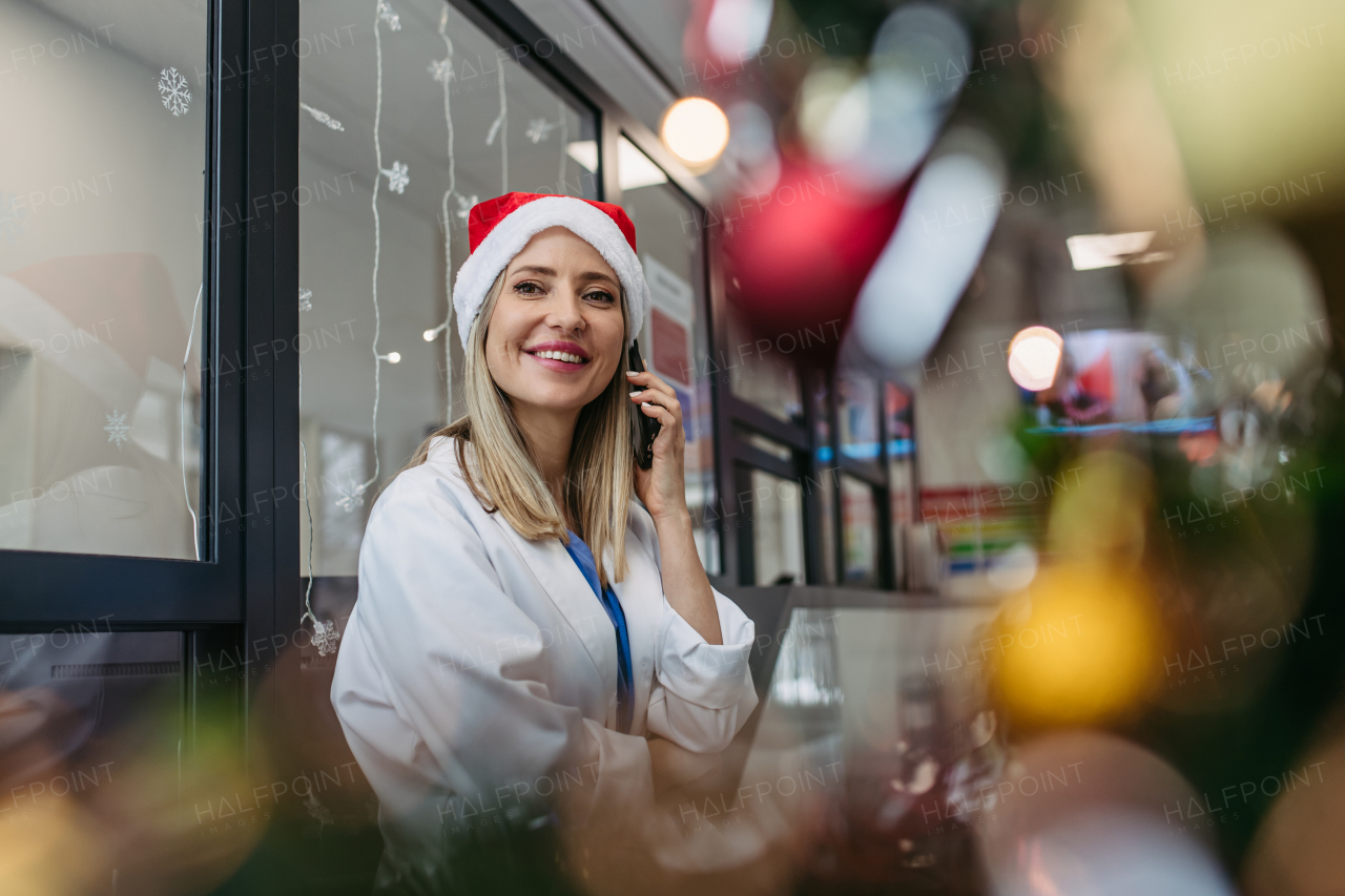 Portrait of beautiful doctor with christmas hat making call. Working in hospital on the Christmas day, Christmas Eve. Female doctor working a Christmas shift and can't be with her family.