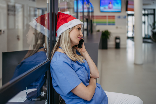 Portrait of beautiful nurse with christmas hat making call. Working in hospital on the Christmas day, Christmas Eve. Female doctor working a Christmas shift and can't be with her family.